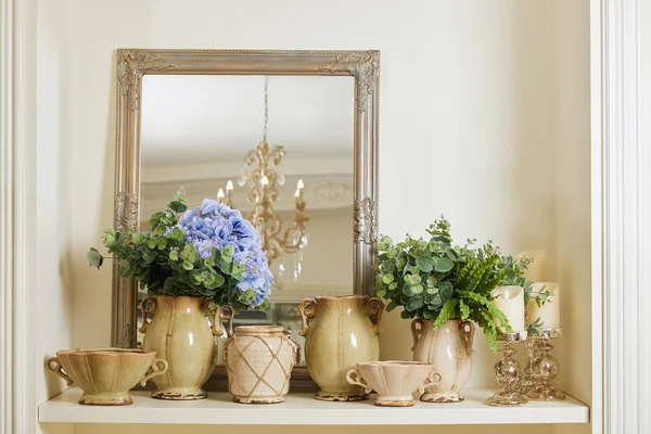 Espelho, conjunto bege e flores na prateleira — Fotografia de Stock