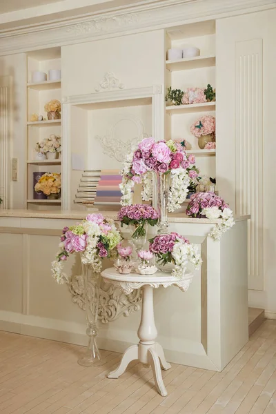 Intérieur de la chambre avec rack, table et fleurs dans des vases en verre — Photo de stock