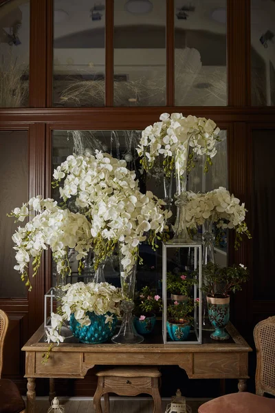 Interior do quarto com flores brancas em vasos de vidro na mesa — Fotografia de Stock