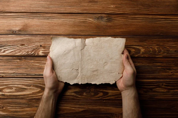 Vue recadrée de l'homme tenant la feuille de papier vieilli dans les mains — Photo de stock