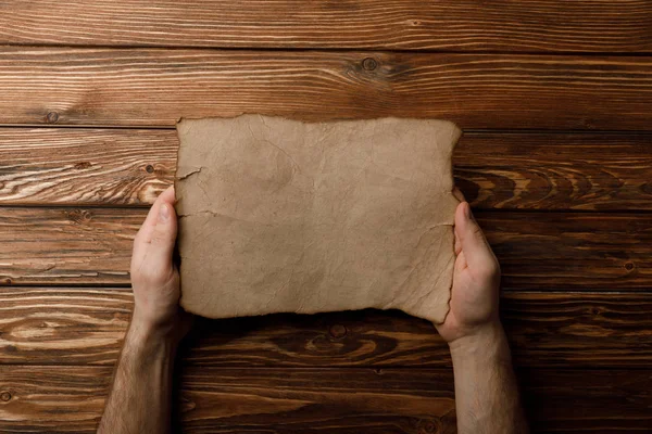 Vue de dessus de l'homme tenant la feuille de papier vieilli dans les mains — Photo de stock