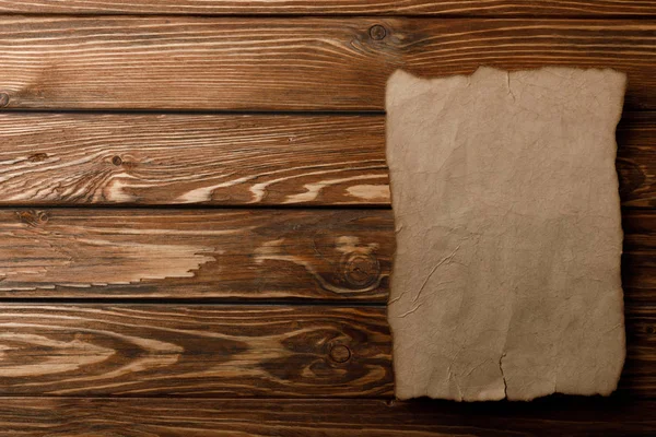 Vista superior de la hoja de papel envejecida acostada sobre fondo de madera - foto de stock