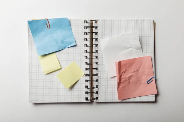 Vue du haut du carnet ouvert avec des papiers carrés et des notes collantes sur fond blanc — Photo de stock