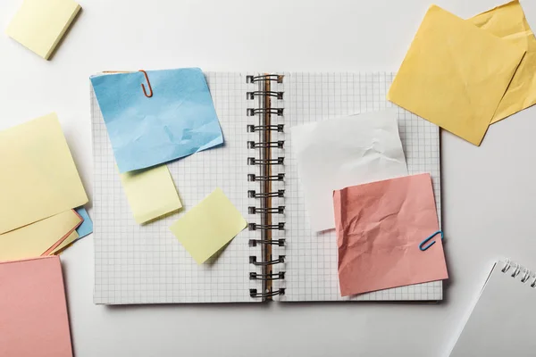 Top view of opened notebook with squared papers and crumpled sticky notes on white background — Stock Photo
