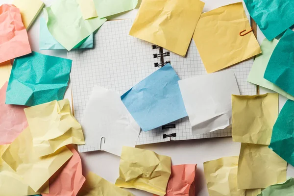 Top view of opened notebook with squared papers near crumpled sticky notes — Stock Photo