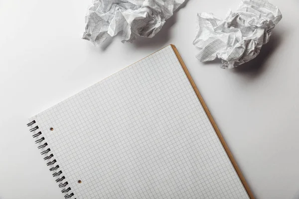 Draufsicht auf Notizbuch mit leerer, quadratischer Seite in der Nähe zerknitterter Blätter auf weißem Hintergrund — Stockfoto