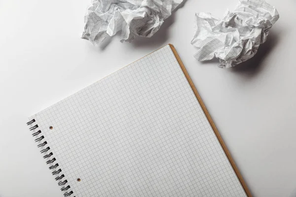 Vista dall'alto del notebook con pagina quadrata vuota vicino a fogli spiegazzati su sfondo bianco — Foto stock