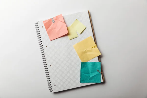 Vue du haut du carnet avec page carrée vierge près de notes collantes froissées sur fond blanc — Photo de stock