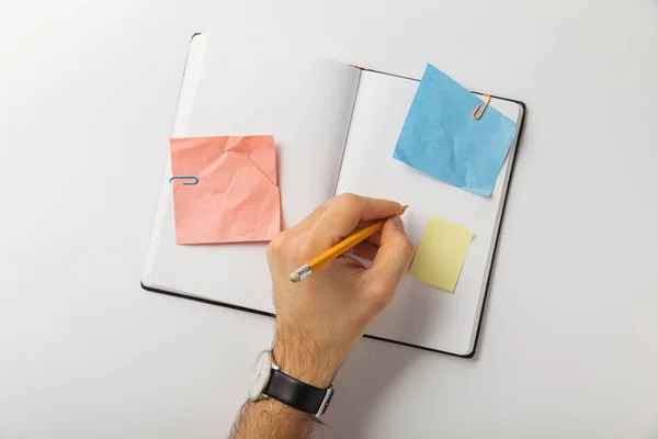 Vista recortada del hombre escribiendo en hoja en blanco con palos de papel sobre fondo blanco — Stock Photo