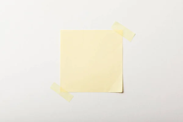 Papel branco amarelo com fita adesiva no fundo branco — Fotografia de Stock