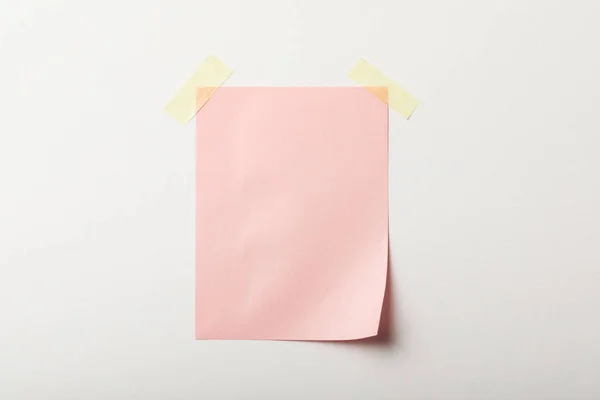 Pink blank paper with sticky tape on white background — Stock Photo