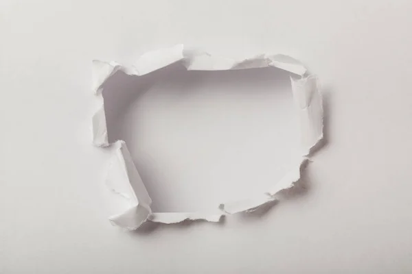 Agujero roto en hoja de papel sobre fondo blanco - foto de stock