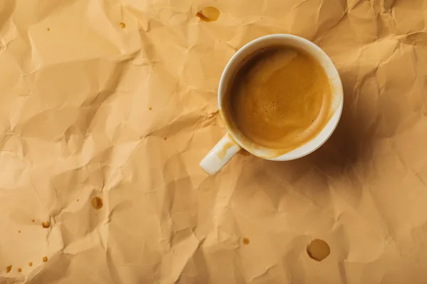 Top view of cup with coffee on beige crumpled page — Stock Photo