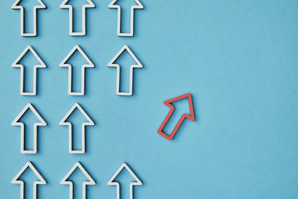 Top view of rows vertical white arrows near red pointer on blue background — Stock Photo