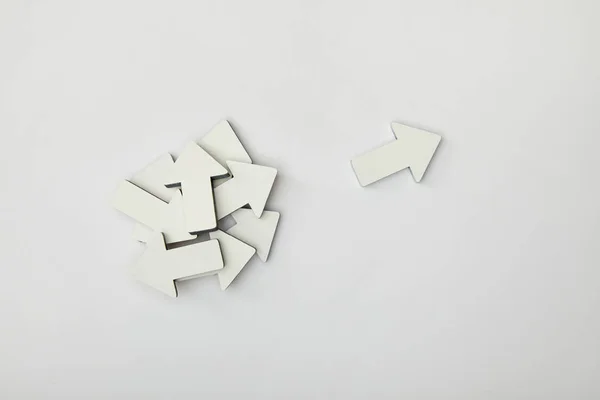 Top view of white pointer near bunch of arrows on grey background — Stock Photo