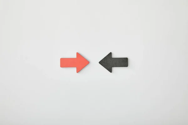 Top view of red arrow opposite black pointer on grey background — Stock Photo