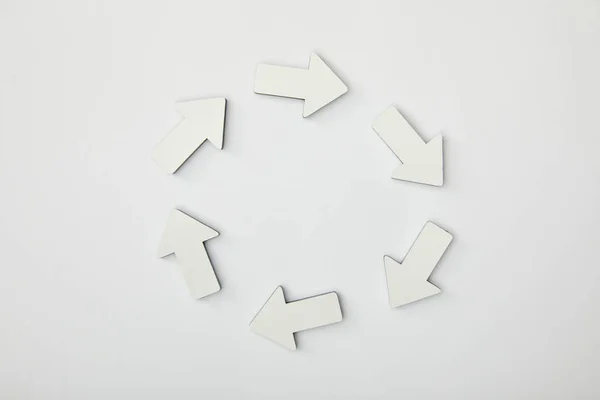 Top view of white arrows in circle on grey background — Stock Photo