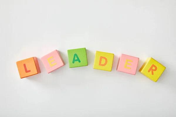 Vista superior de letras líder feitas de cubos multicoloridos no fundo branco — Fotografia de Stock