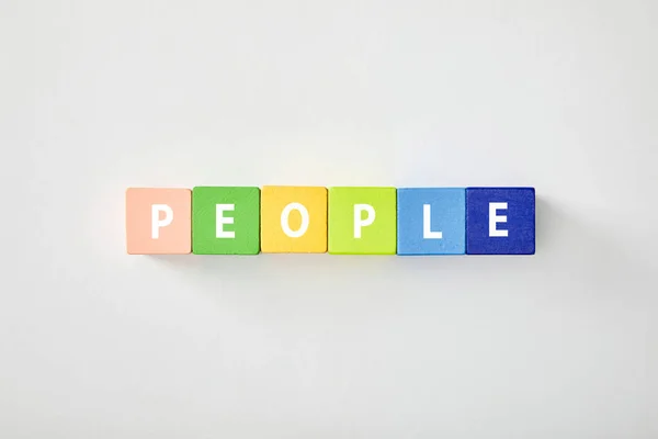 Vue du dessus des personnes lettrage en cubes multicolores sur fond blanc — Photo de stock
