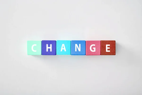 Top view of change lettering made of multicolored cubes on grey background — Stock Photo