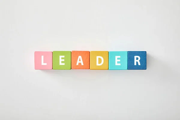 Top view of leader lettering made of multicolored blocks on grey background — Stock Photo