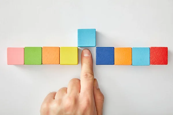 Vista cortada da mão masculina com cubos multicoloridos no fundo cinza — Fotografia de Stock