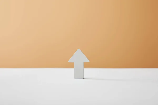 Flèche sur table blanche et fond beige — Photo de stock