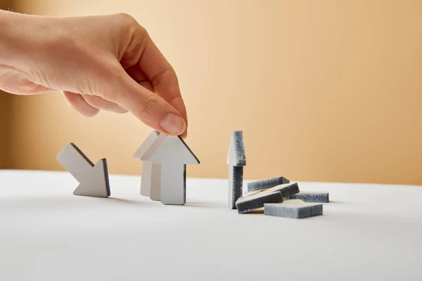 Cropped view of man putting arrows on white table and beige background — Stock Photo