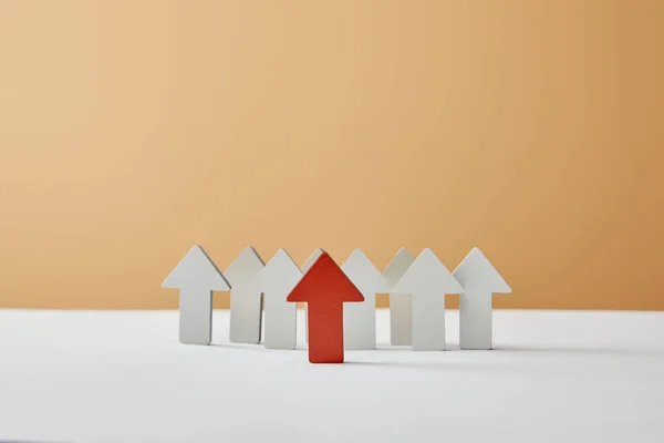 Figuras de flecha roja con blanco apuntando sobre la mesa y fondo beige - foto de stock