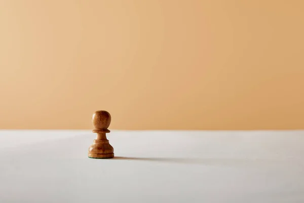 Wooden pawn piece on white table and beige background — Stock Photo