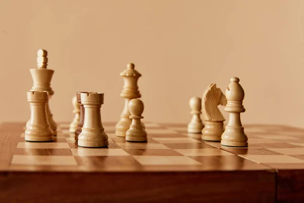 Chess on chess board and beige background — Stock Photo