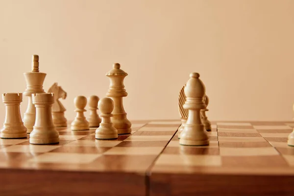 Ajedrez sobre tablero de ajedrez de madera y fondo beige - foto de stock