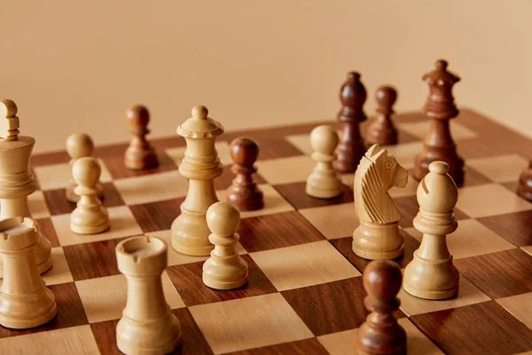 Enfoque selectivo del ajedrez en tablero de ajedrez y fondo beige - foto de stock