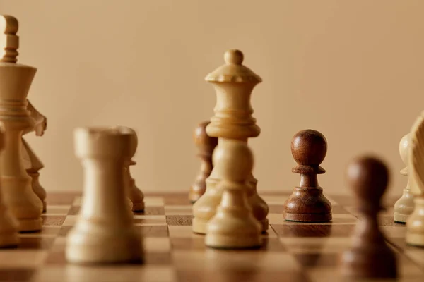 Foco seletivo de peças de xadrez no tabuleiro de xadrez e fundo bege — Fotografia de Stock