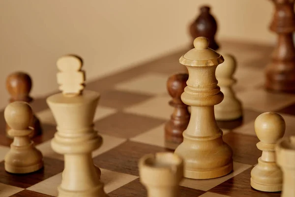 Selective focus of wooden chess pieces on chess board and beige background — Stock Photo