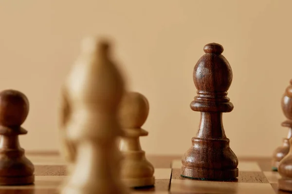 Foco seletivo da peça de xadrez marrom no tabuleiro de xadrez e fundo bege — Fotografia de Stock