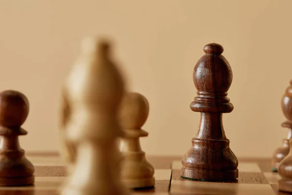 Enfoque selectivo de pieza de ajedrez marrón en tablero de ajedrez y fondo beige — Stock Photo