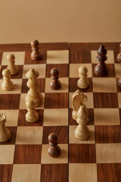 Peças de xadrez no tabuleiro de xadrez de madeira e fundo bege — Fotografia de Stock