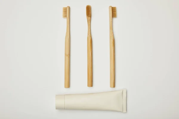 Top view of toothpaste in tube and bamboo toothbrushes on white background — Stock Photo