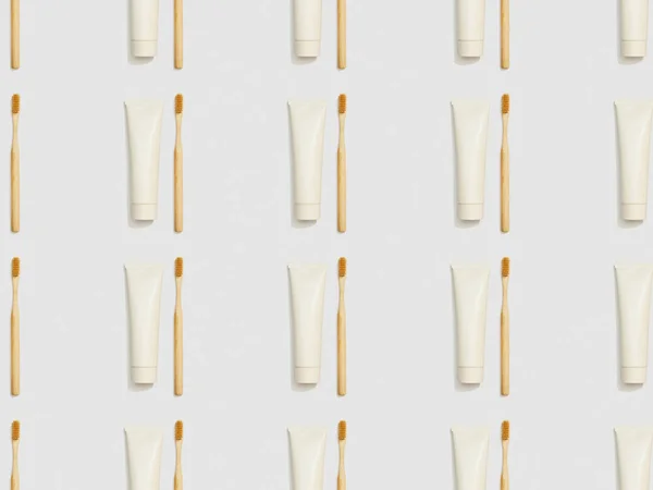 Bamboo toothbrushes and toothpaste in tubes on grey background, seamless background pattern — Stock Photo