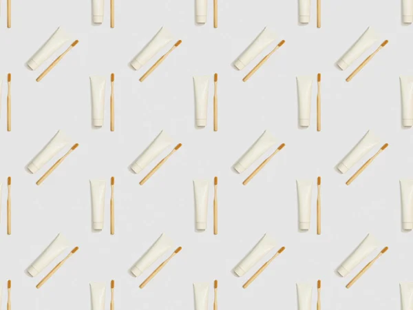 Бамбуковые зубные щетки и зубная паста в разных направлениях на сером фоне, бесшовный рисунок фона — стоковое фото