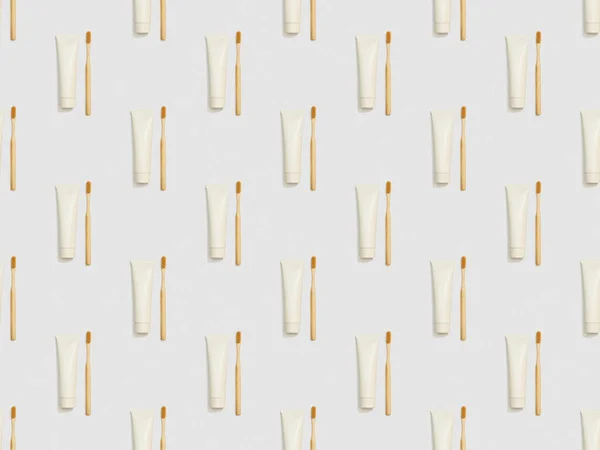 Vertically located bamboo toothbrushes and toothpaste in tubes on grey background, seamless background pattern — Stock Photo