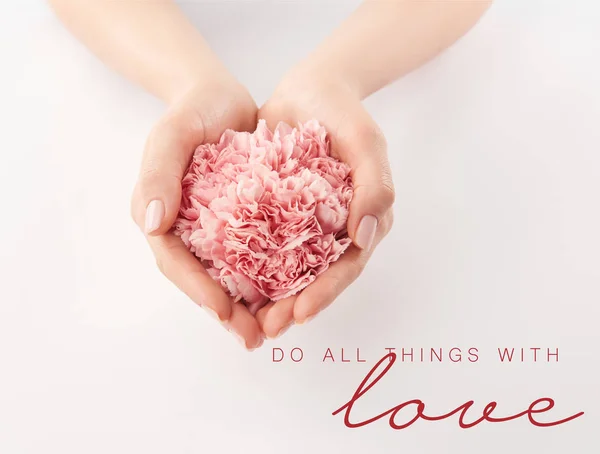 Cropped view of female hands with pink carnations and do all things with love lettering — Stock Photo