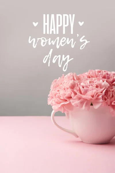 Flores de clavel de color rosa en copa sobre fondo gris con letras felices día de las mujeres - foto de stock