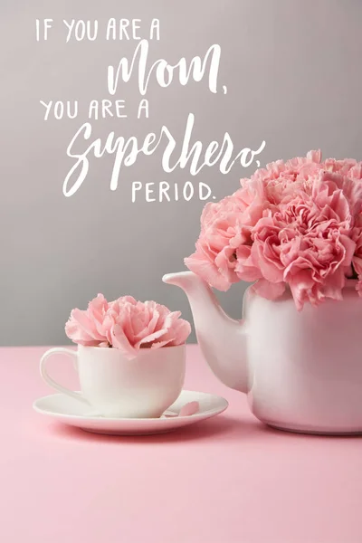 Flores de clavel rosa en taza y tetera sobre fondo gris con si usted es una madre, usted es un superhéroe, período de letras — Stock Photo