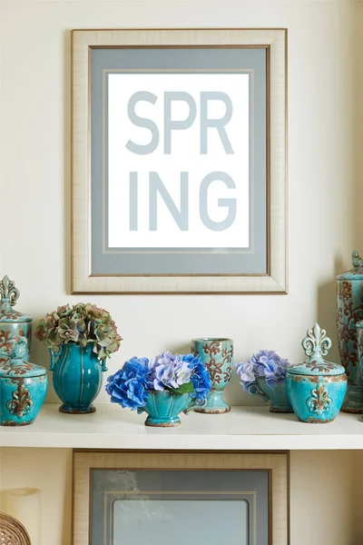 Picture frame with spring lettering and turquoise ceramic ornate vintage vases with flowers on shelf — Stock Photo