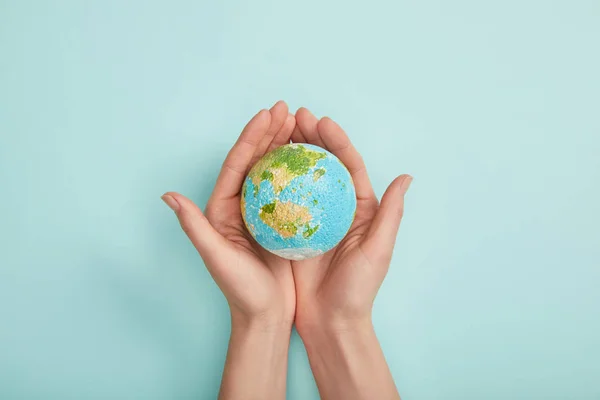 Draufsicht der Frau mit Planetenmodell auf türkisfarbenem Hintergrund, Earth Day Konzept — Stockfoto