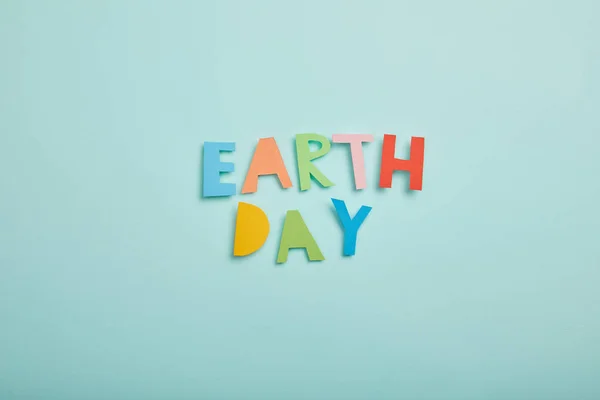 Top view of colorful paper letters on turquoise background, earth day concept — Stock Photo