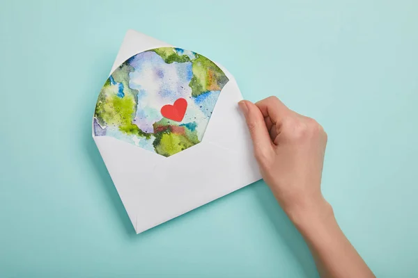Draufsicht der Frau mit Umschlag mit Planetenbild auf türkisfarbenem Hintergrund, Earth Day Konzept — Stockfoto
