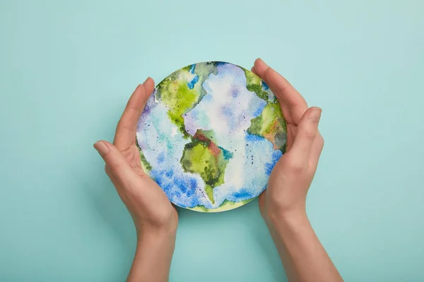 Vue du dessus de la femme tenant l'image de la planète sur fond turquoise, concept de jour de la terre — Photo de stock